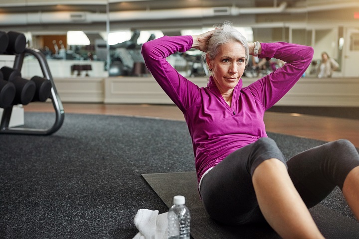 Elderly woman doing crunches in a gym